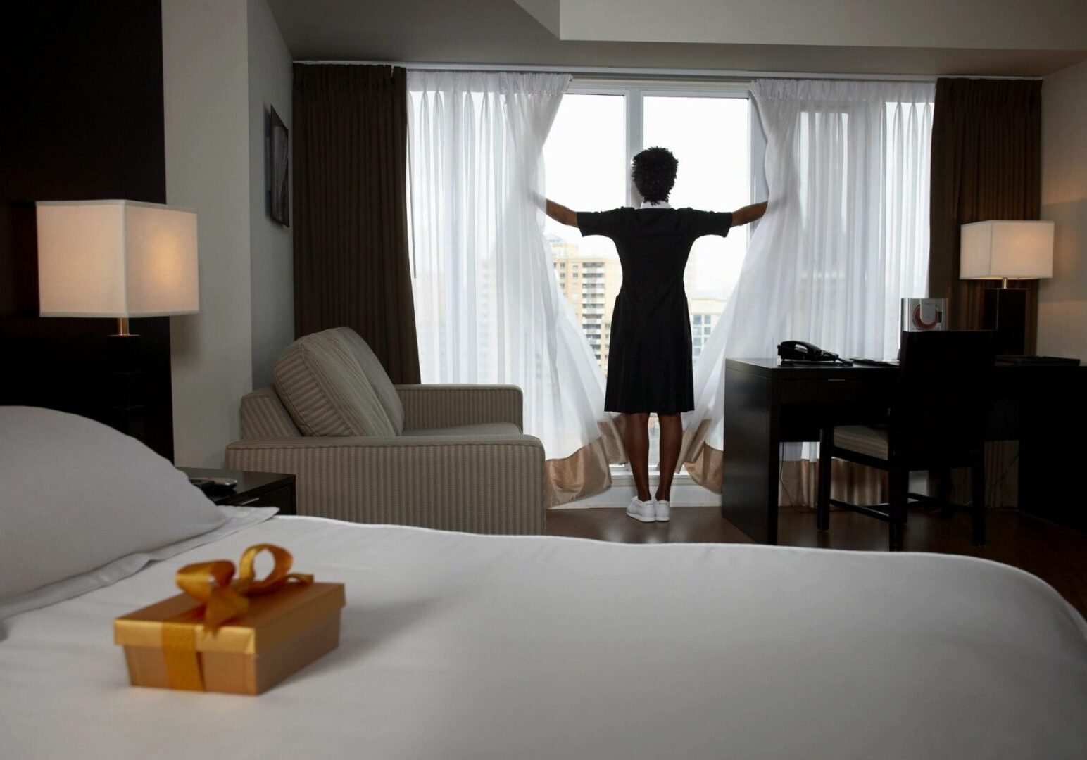 A woman standing in front of the window opening to see outside.